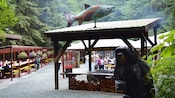 Uma área de acampamento com uma churrasqueira aberta coberta, mesas de piquenique e uma placa que diz Salmon Bake