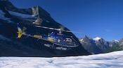 A helicopter hovers a few feet above a glacial ice field