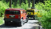 Dos Hummers avanzan por un camino de grava a través del bosque