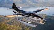A close-up of a seaplane from Misty Fjords Air in flight over a fjord