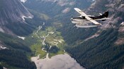 Un hidroavión sobrevolando un frondoso valle del río