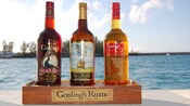 3 bottles of alcohol on a slab of wood with a sign that reads Gosling's Rum Bermuda Since 1806