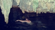 A man swims in a cave
