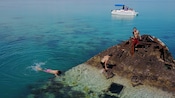 People on a boat near a wrecked ship with people standing on it