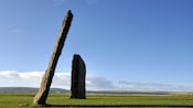 A tall monolith leaning toward a shorter monolith in an open field