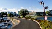 A walking and bike path that runs through a canal with a small boat harbor on one side, amidst a city