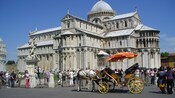Turistas caminhando ao redor da catedral medieval na Praça dos Milagres de Pisa