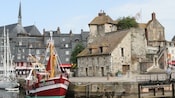 A fishing boat moored along a boardwalk in front of a stone building