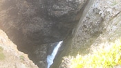 The view downward from a cliff at a rushing stream below