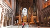 Visitors take pictures of a large Gothic cathedrals pews and pulpit