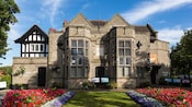 A building with windows, a front lawn and garden featuring a variety of flowers