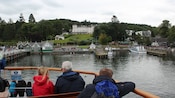 Passengers on the upper deck of a boat watch the activity of a wharf
