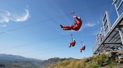 People on zip lines launch from a platform