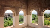 A room with ornate window arches overlooking trees and a large city