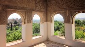 Uma sala com janelas em arcos ornamentados com vista para árvores e uma grande cidade