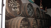 Stacked barrels with writing on them near hanging boats