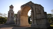 A stone archway near trees and a building