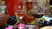 A table set with 2 stemmed glasses filled with wine, grapes and chocolate