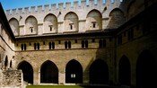 A courtyard with stone arches and ramparts