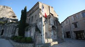 Stone buildings, bushes, a cobblestone street and a flag