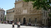 A city street with cafes, people walking and a historical building