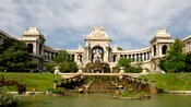 Un parque con un lago, fuentes, personas, árboles, estatuas y un palacio
