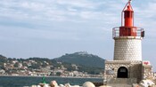 Un faro cerca de una isla llena de árboles y edificios