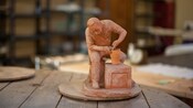 A sculpture of a potter bent over his work