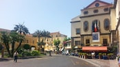 On a tree lined street a sign hangs over a sidewalk cafe advertising a Picasso exhibit
