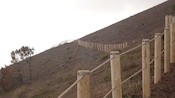Un poste de madera y una valla de cuerdas en la cima de una montaña, desde la que se ve la civilización hacia abajo