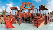 A Mayan themed water playground featuring a shallow pool with slides, rope bridges, fountains and more
