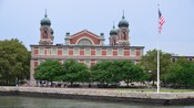 A brick building three floors high and towers topped by domes at each corner