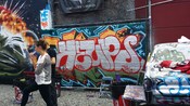 Un hombre y una mujer parados frente a una pared decorada con grafitis y murales