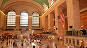 A large lobby with a circular kiosk in the middle and three large windows on one wall