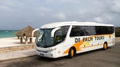 A bus with tinted windows parked alongside a curb at the beach