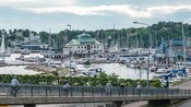 Personas con cascos andando en bicicleta por un puerto con barcos