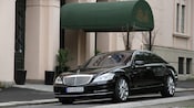 A Mercedes four door sedan parked in front of a hotel awning