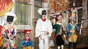 Marionetes personagens do show Punch e Judy em frente a um fundo de teatro com a imagem de uma cidade italiana