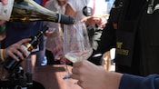 A wine tasting in progress, with servers pouring wine into wine glasses