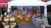 A kiosk with artisan crafts such as weaved baskets, margents and wind chimes