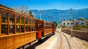 A vintage trolley train traveling on the tracks in a quaint mountain town
