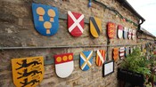 Una colección de escudos de armas decorativos en una pared de piedra en Corfe Castle