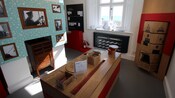 O interior do Farol Portland Bill e do centro de visitantes revela uma sala ensolarada cheia de fotos antigas, caixas de giz de cera e quebra-cabeças de madeira