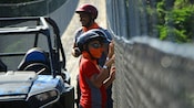 A man stands next to 2 boys and a quad on a bridge