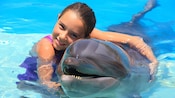 Uma menina em águas rasas abraça um golfinho