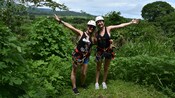 2 women smile in front of a jungle and a lush valley