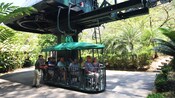 A group of 8 sits in an open air gondola and prepares to tour the rainforest