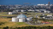 A tubular building capped with a dome and the surrounding city