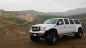 Uma caminhonete fantástica Ford Excursion do último modelo com 6 portas em uma paisagem de montanha chuvosa
