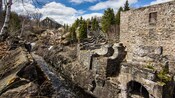 Ruins and an old building next to a stream and trees